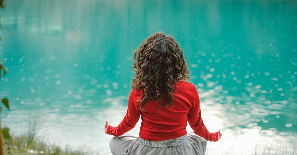 Person meditiert entspannt in der Natur auf einer Wiese